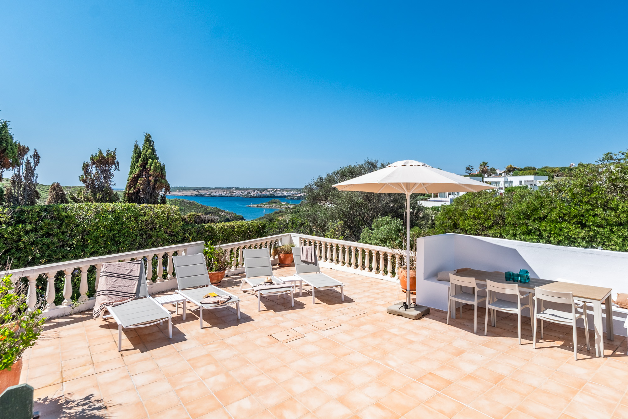 Villa surélevée à Cala Llonga avec vue sur la mer et le port de Mahón, et une grande terrasse avec piscine.